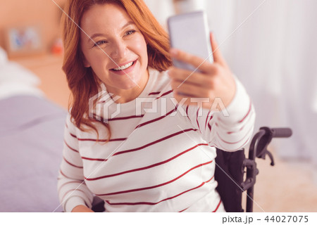 Joyful wheelchaired woman making selfies 44027075