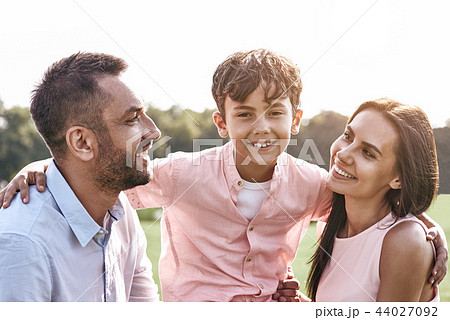 Bonding. Family of three walking on grassy field son hugging par Bonding. Family of three walking on grassy field son hugging par 44027092