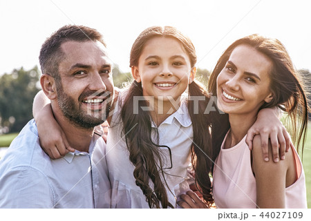 Togetherness, Family of three standing on grassy field hugging s Togetherness, Family of three standing on grassy field hugging s 44027109