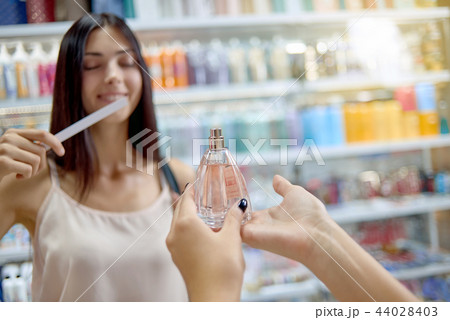 Closeup of perfumes in hands of female consultant in cosmetics store 44028403