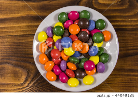 Saucer with colorful button shaped candies Saucer with colorful button shaped candies 44049139