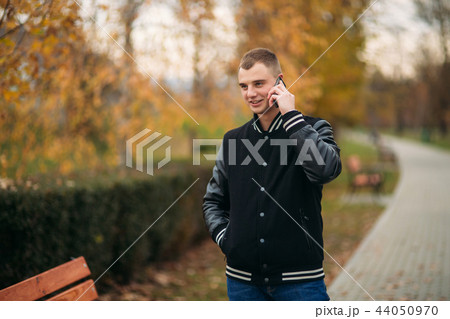A young guy in a black jacket uses the phone 44050970