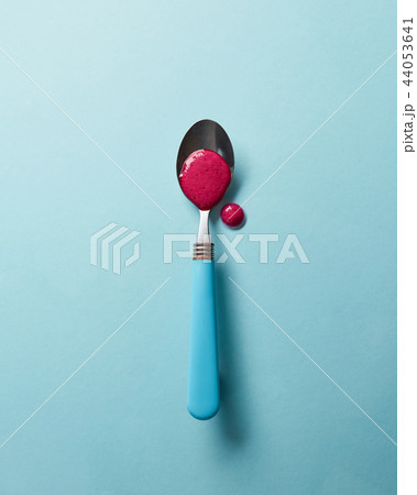 Flat lay view of smoothies of red berries in a spoon on a glass blue background. 44053641