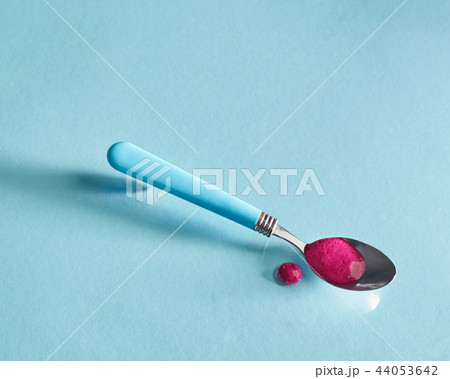 Healthy organic smoothies of red berries in a spoon on a glass blue background. 44053642