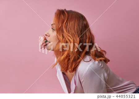 Studio fashion photo of beautiful young woman with flowers in her mouth isolated on pink 44055321