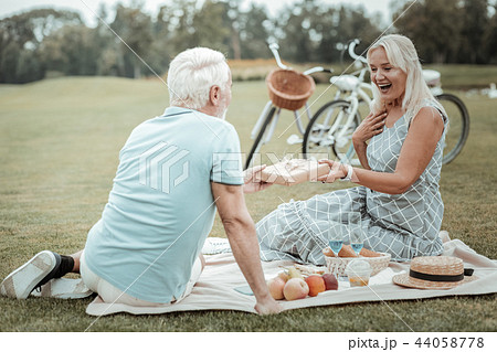 Cheerful senior female person taking box with present Cheerful senior female person taking box with present 44058778