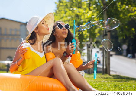 Delighted nice women blowing soap bubbles together Delighted nice women blowing soap bubbles together 44059945