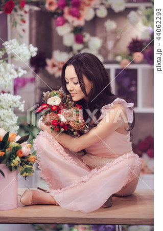 Beautiful asian woman florist in pink dress with bouquet of flowers in hands in flower store 44062293