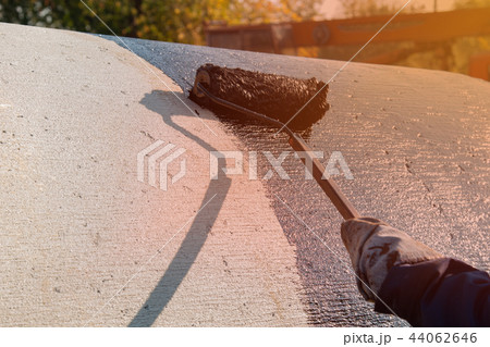 Roofer worker painting black coal tar or bitumen 44062646