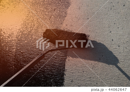 Roofer worker painting black coal tar or bitumen 44062647