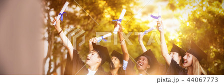 Smiling graduate school kids standing with degree scroll in campus 44067773