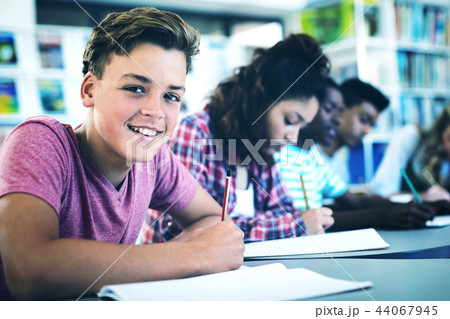 Portrait of happy schoolboy studying in library 44067945