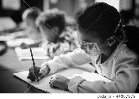 Attentive schoolgirl doing her homework in classroom 44067978