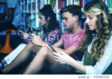 Students using mobile phone in library 44068336