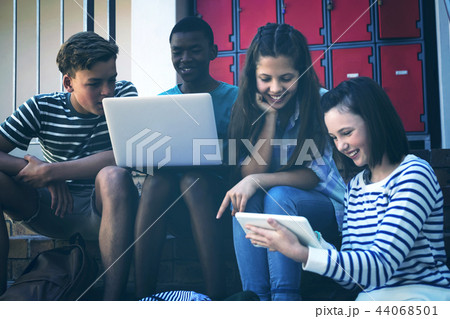 Students using laptop, mobile phone and digital tablet on staircase 44068501