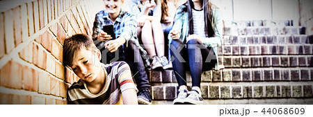 School friends bullying a sad boy in school corridor 44068609