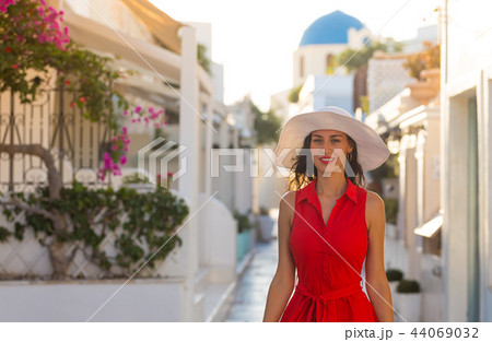 Santorini travel tourist brunette woman in red dress visiting famous white Oia village. Santorini travel tourist brunette woman in red dress visiting famous white Oia village. 44069032