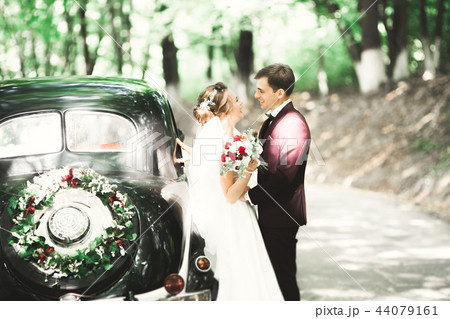 Stylish wedding couple, bride, groom kissing and hugging on retro car 44079161