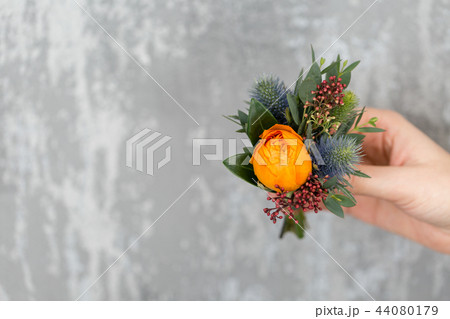 outonniere of orange roses to the man to the groom. gray background. copy space 44080179