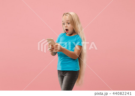 The happy teen girl standing and smiling against pink background. 44082241