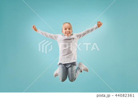 Adorable small child at blue studio. The girl is jumping and smiling. 44082361