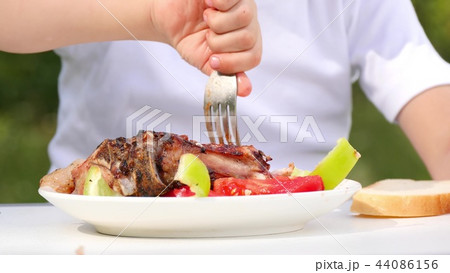 Close-up of white plate with shish kebab, barbecue. The child is eating shish kebab, in close-up 44086156