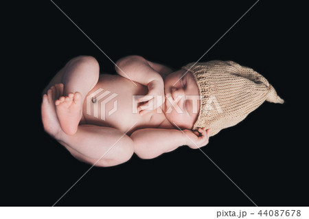 portrait of newborn baby in a yellow or gold hat on a black background. Newborn fashion 44087678