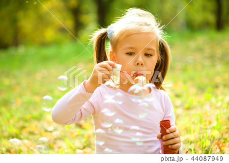 Little girl is blowing a soap bubbles Little girl is blowing a soap bubbles 44087949