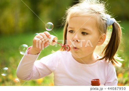 Little girl is blowing a soap bubbles Little girl is blowing a soap bubbles 44087950