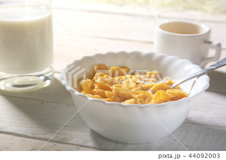 Corn Flakes cereal in a bowl and glass with milk. 44092003