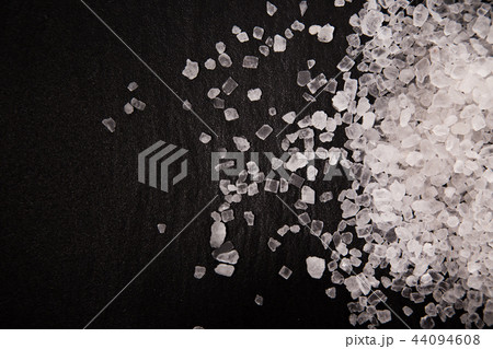 White diamond coarse grain salt heap on black stone background. 44094608