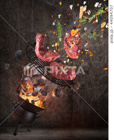 Kettle grill with hot briquettes, cast iron grate and tasty meats flying in the air. Kettle grill with hot briquettes, cast iron grate and tasty meats flying in the air. 44094707