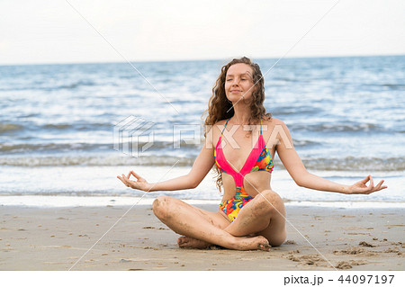 Young woman practices yoga on the beach in summer. 44097197