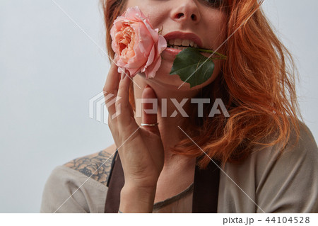 Woman with a beautiful pink rose in her mouth on a gray background with copy space for text Woman with a beautiful pink rose in her mouth on a gray background with copy space for text 44104528