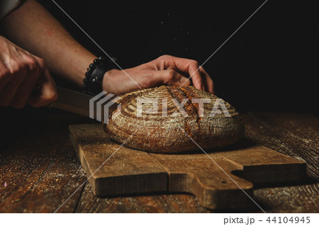 Hands of a young man cut fresh rye bread Hands of a young man cut fresh rye bread 44104945