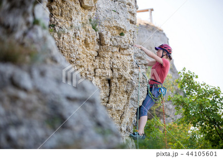 Photo of side view of young athlete woman in red helmet climbing up mountain Photo of side view of young athlete woman in red helmet climbing up mountain 44105601
