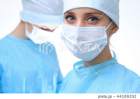 Surgeon doctor in mask performing operation. Focus on female intern girl. Medicine, emergency help Surgeon doctor in mask performing operation. Focus on female intern girl. Medicine, emergency help 44109202