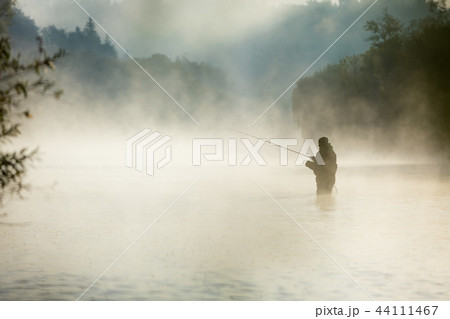Fisherman holding fishing rod, standing in river Fisherman holding fishing rod, standing in river 44111467