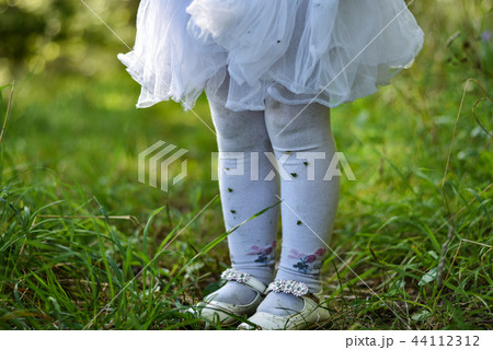 The legs of a little girl in a white dress The legs of a little girl in a white dress 44112312