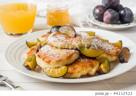 Cheese pancakes in powdered sugar with fresh plums Cheese pancakes in powdered sugar with fresh plums 44112522