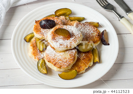 Cheese pancakes in powdered sugar with fresh plums Cheese pancakes in powdered sugar with fresh plums 44112523
