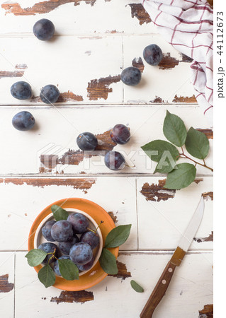 Fresh plum berries on a plate with leaves Fresh plum berries on a plate with leaves 44112673