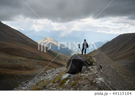 Photographer with camera and tripod in mountains Photographer with camera and tripod in mountains 44115104
