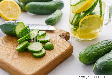 Cutting board with sliced cucumbers for detox water. Process of preparing energy cocktail 44126162