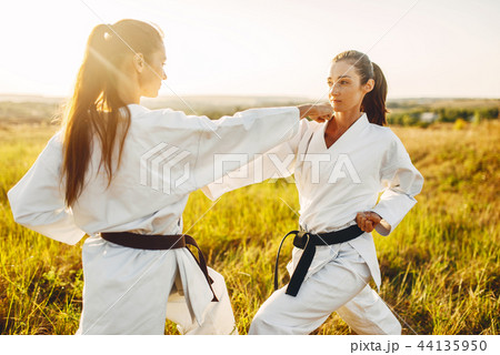 Two female karate with black belts fight in field 44135950