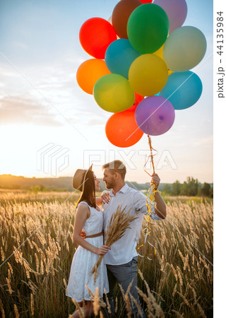 Couple holds balloons and kissing in wheat field 44135984