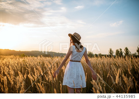 Woman in dress walking in wheat field on sunset 44135985