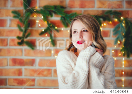 young cozy woman in white sweater with Christmas lights 44140343