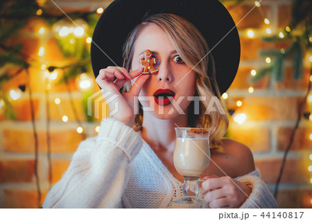 woman with cup of coffee, cookie and Christmas lights woman with cup of coffee, cookie and Christmas lights 44140817