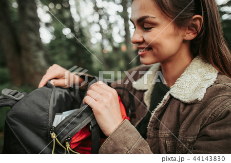 Young female traveler unzipping backpack on blurred background 44143830